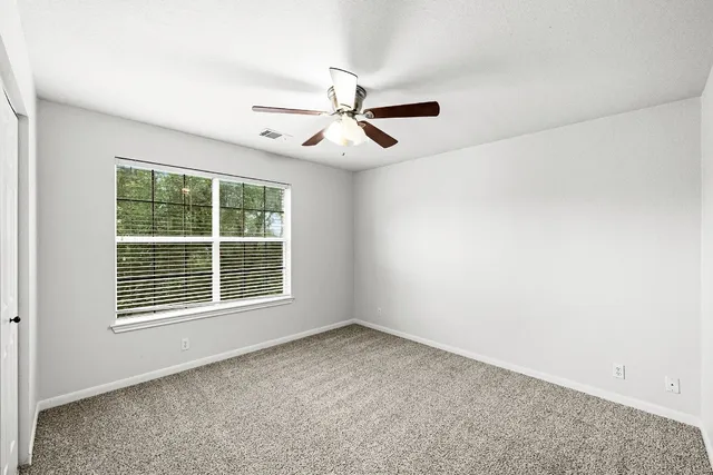 an empty room with windows and fan