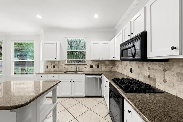 a kitchen with granite countertop a sink stove and cabinets