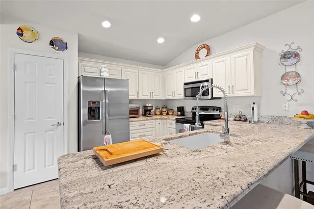 a kitchen with granite countertop a refrigerator and a stove top oven