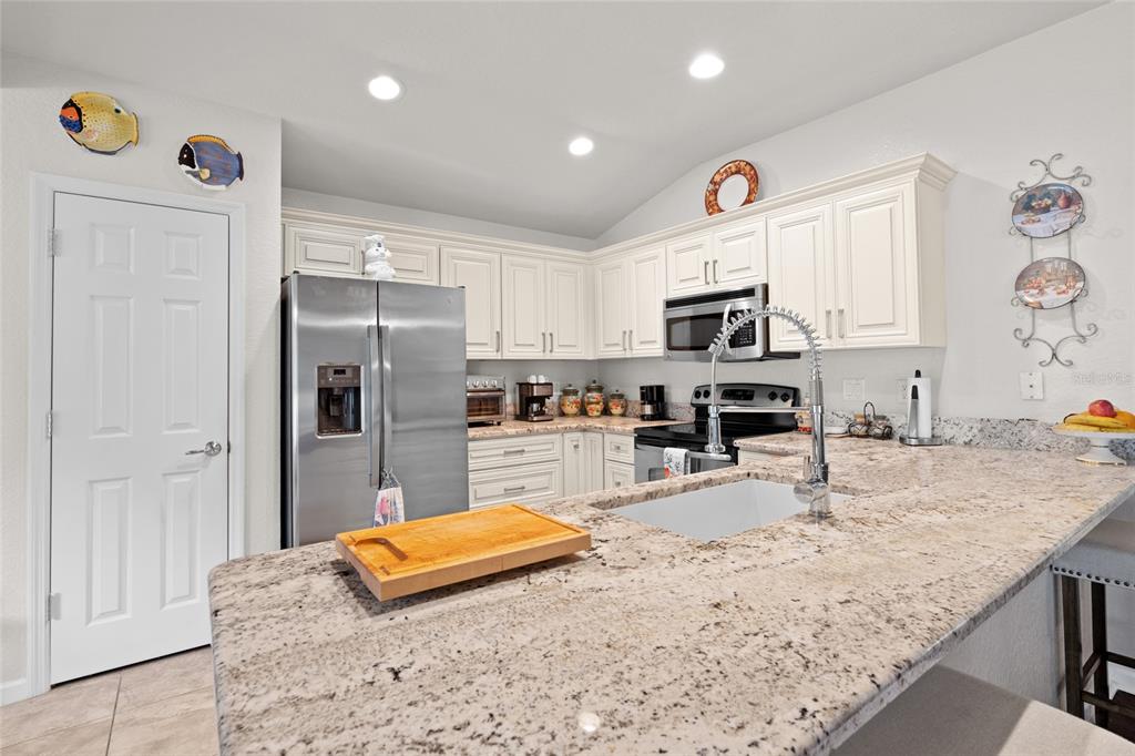 4683 Southwest 40th Place Ocala, FL 34474 - Photo 9 of 43 a kitchen with granite countertop a refrigerator and a stove top oven