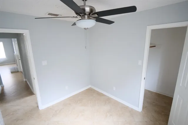 an empty room with a ceiling fan and carpet
