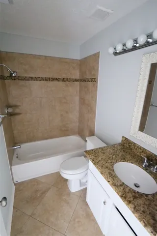 a bathroom with a granite countertop sink a toilet and bathtub