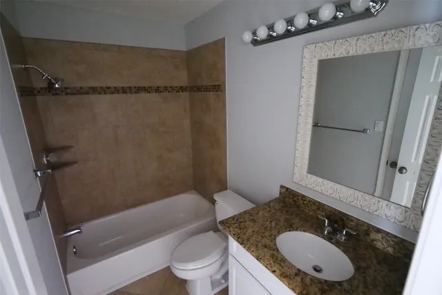 a bathroom with a granite countertop sink toilet mirror vanity and shower