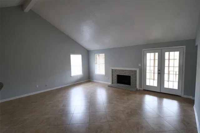 an empty room with floor to ceiling windows and fireplace