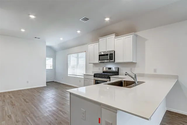 a kitchen with stainless steel appliances a white stove top oven sink and cabinets