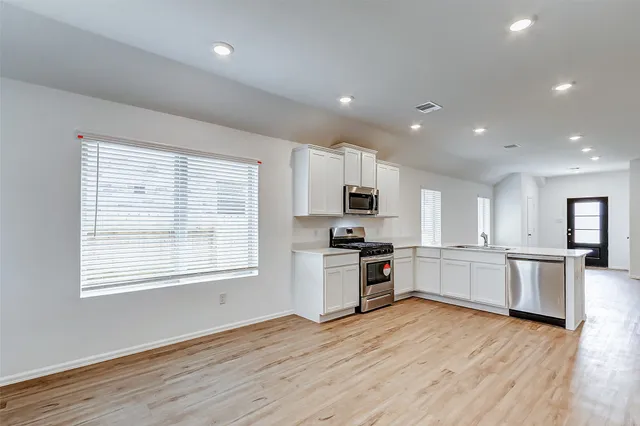 a large kitchen with cabinets wooden floor and stainless steel appliances