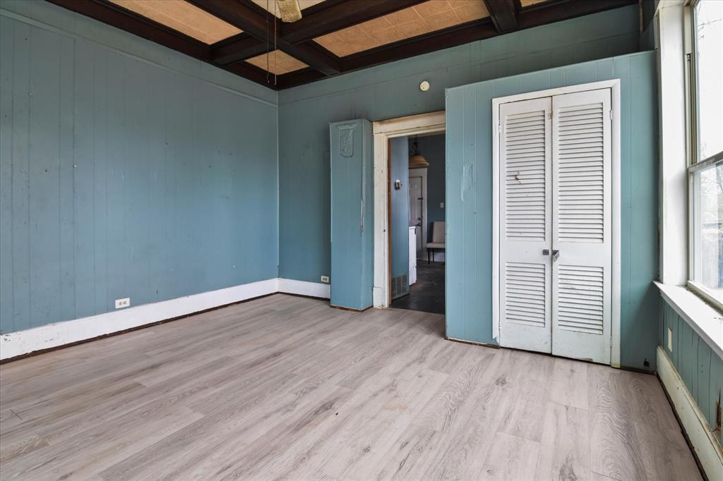 738 1st Street Southwest Paris, TX 75460 - Photo 6 of 25 Unfurnished bedroom featuring coffered ceiling, light wood finished floors, baseboard heating, wooden walls, and a ceiling fan