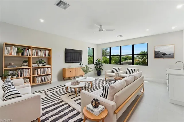 a living room with furniture floor to ceiling window and a flat screen tv