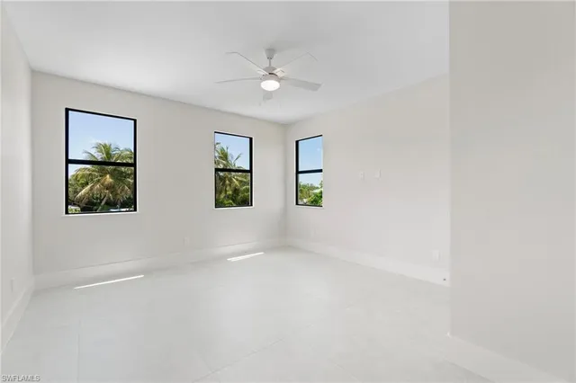an empty room with windows and fan