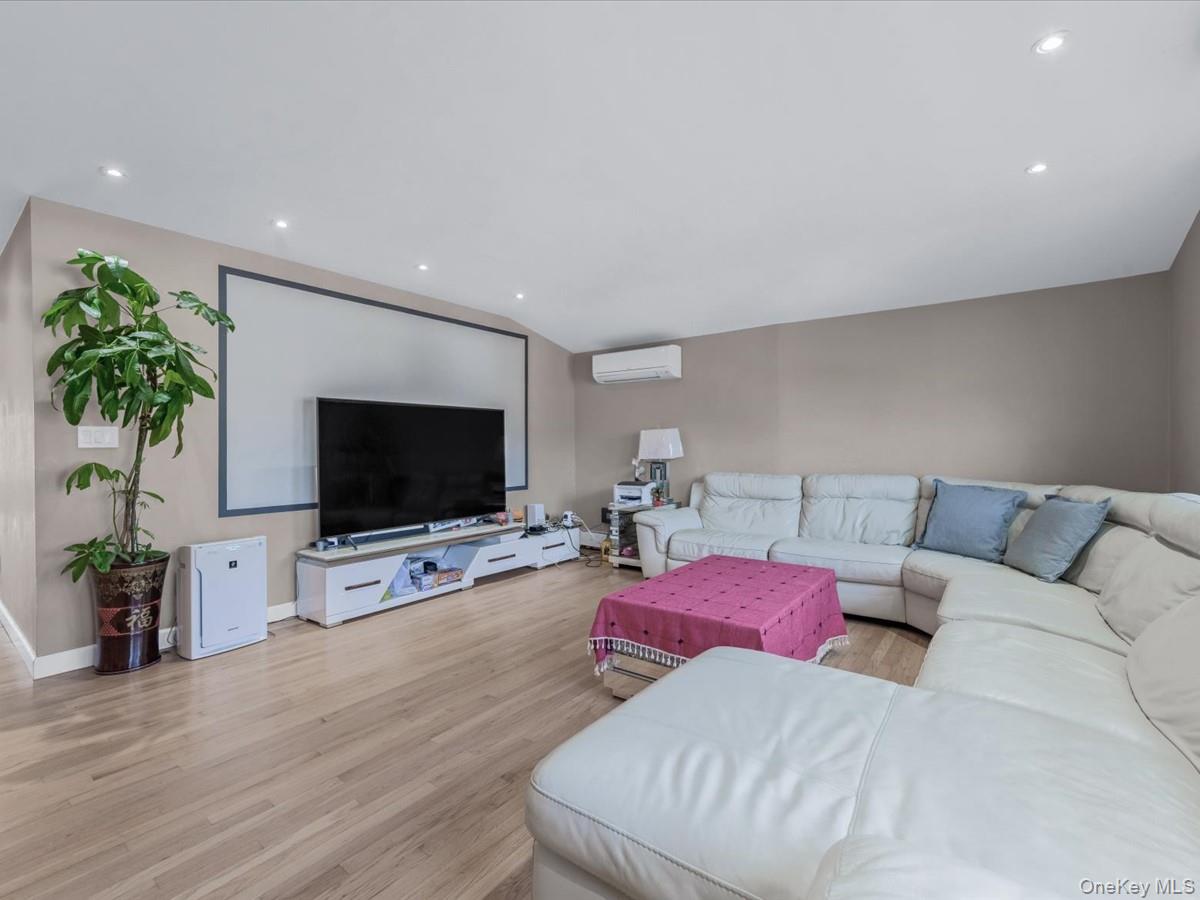 217-32 Corbett Road Queens, NY 11361 - Photo 4 of 25 Living area featuring light wood-type flooring, recessed lighting, a wall mounted air conditioner, and vaulted ceiling