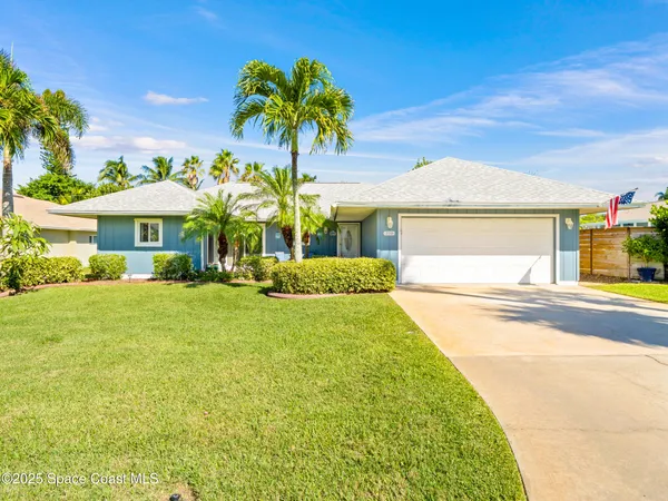 a view of a house with a yard and palm trees
