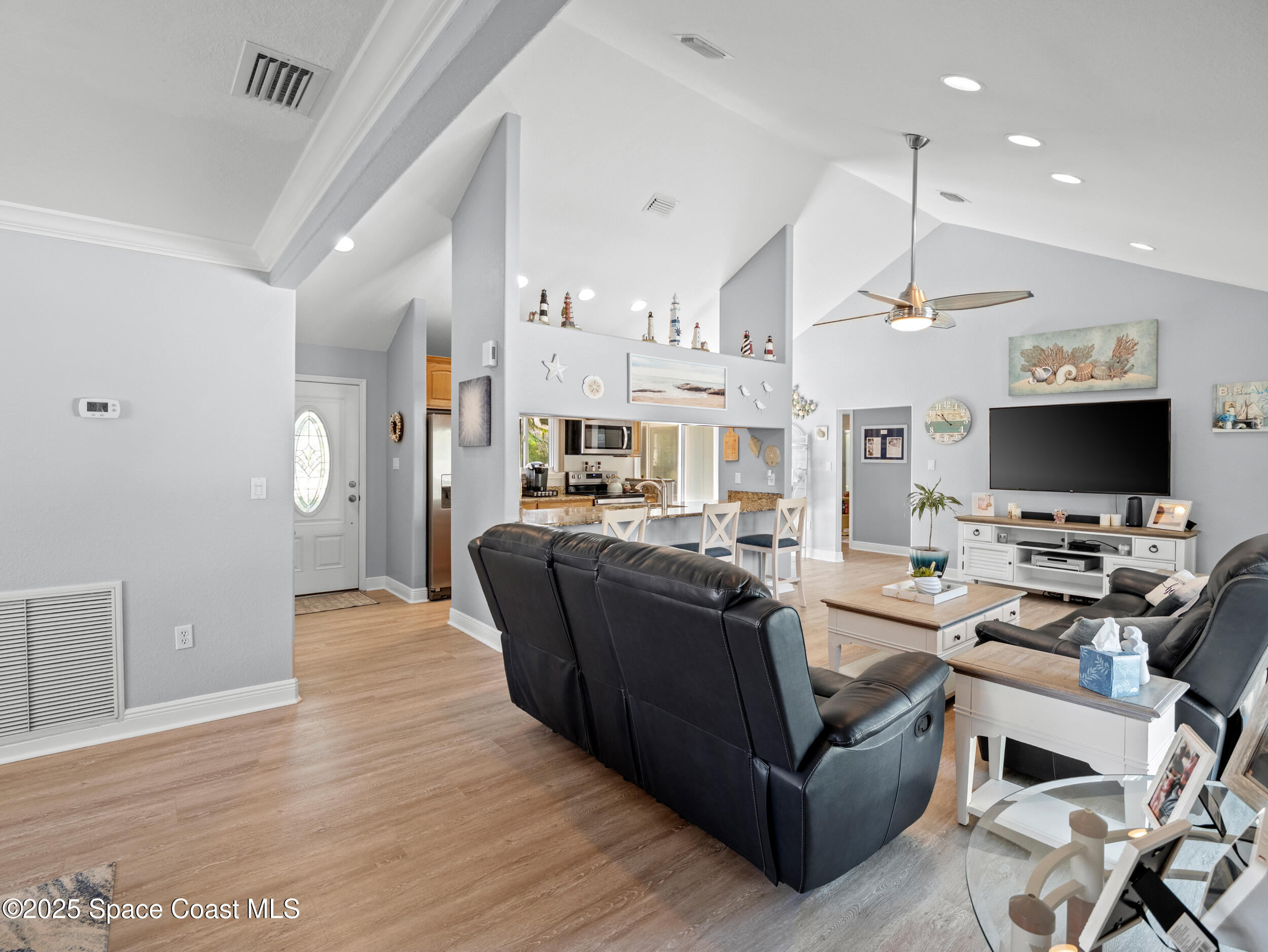230 Riggs Avenue Melbourne Beach, FL 32951 - Photo 4 of 38 a living room with couches a flat screen tv and kitchen view