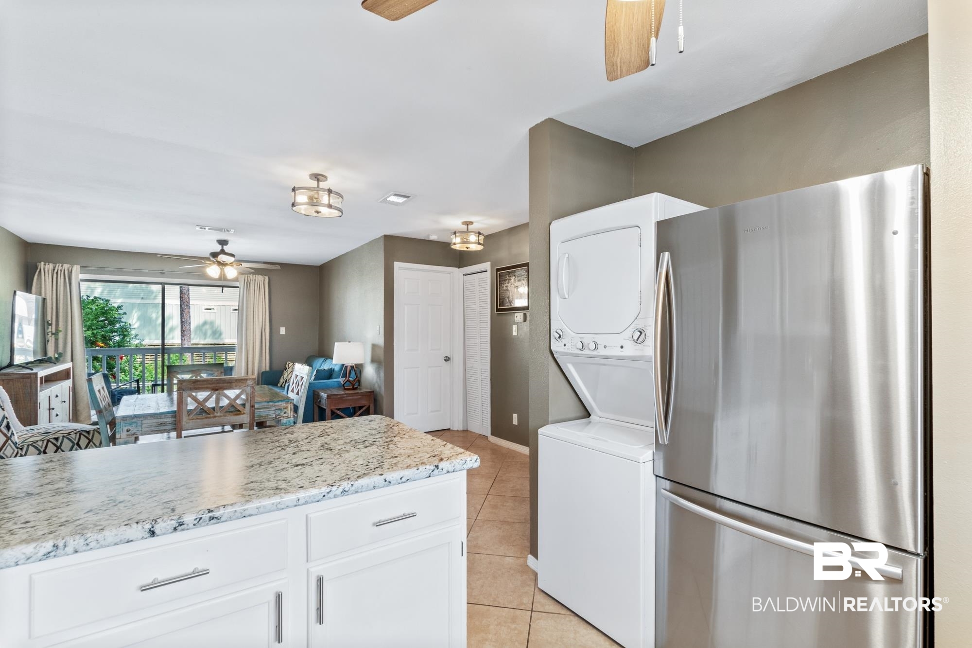 25925 -C Canal Road, Unit 203 Orange Beach, AL 36561 - Photo 8 of 57 Kitchen with stacked washer and clothes dryer, stainless steel fridge, light stone countertops, white cabinetry, and ceiling fan