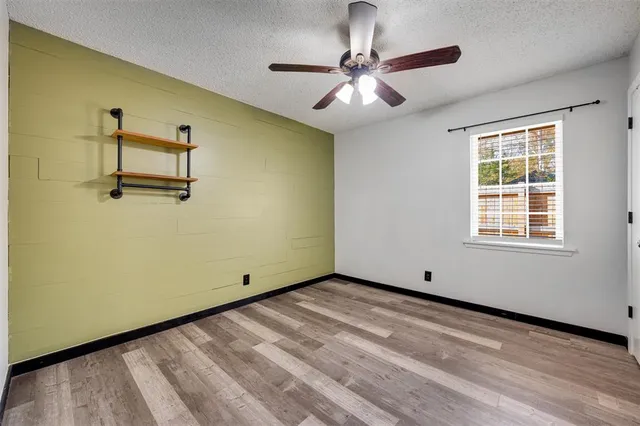 a view of a room with a large window and chandelier fan