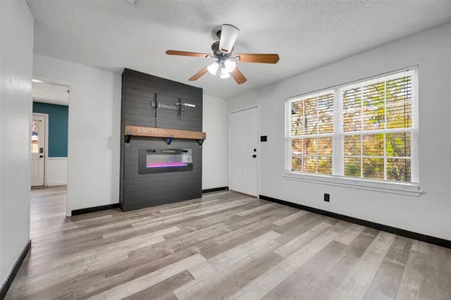 a view of an empty room with window and wooden floor