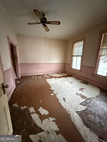 an empty room with windows and ceiling fan