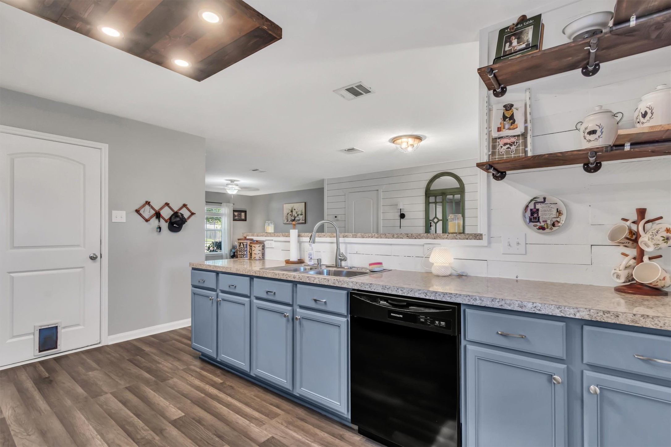 100 Wincliff Cove, Unit 13D Jarrell, TX 76537 - Photo 5 of 21 A well-appointed kitchen features farm house style cabinetry, a stainless steel sink, and wood plank flooring, providing a functional and stylish space.