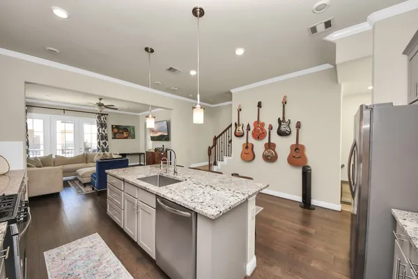 a kitchen with stainless steel appliances granite countertop a stove top oven a sink dishwasher and white cabinets with wooden floor