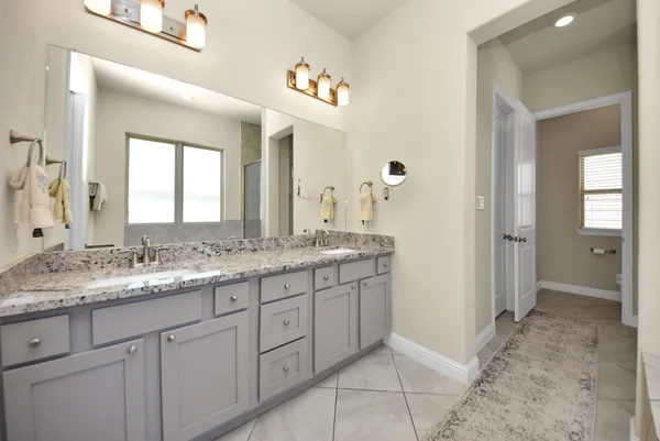 a bathroom with a granite countertop double vanity and a mirror