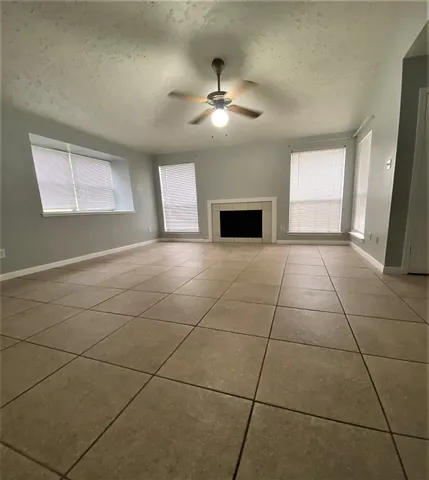 a view of an empty room with window and chandelier fan