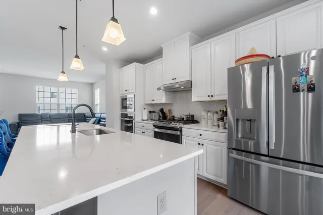 a kitchen with stainless steel appliances granite countertop a refrigerator a stove a sink dishwasher a refrigerator white cabinets and wooden floor