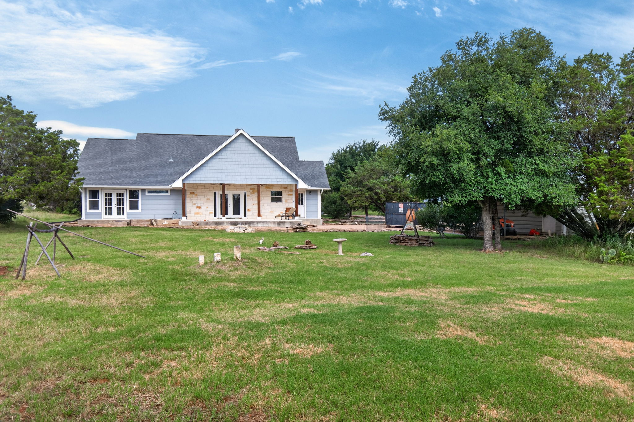 207 Deer Ridge Drive Burnet, TX 78611 - Photo 7 of 36 A large back lawn stretches before a charming house featuring a blend of siding and stone.