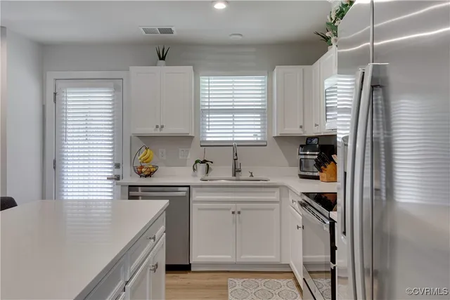 a kitchen with a sink a stove a refrigerator a window and cabinets