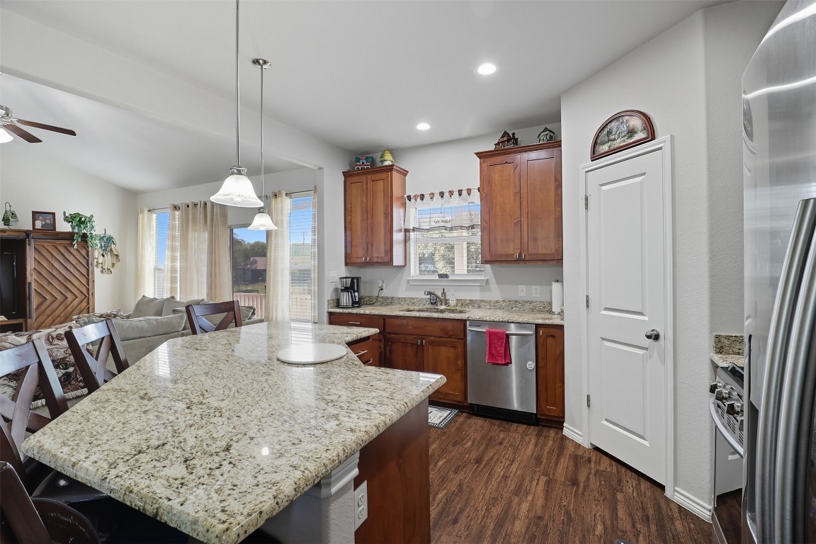 113 Rio Vista Road Burnet, TX 78611 - Photo 28 of 28 Kitchen with open floor plan, a breakfast bar, decorative light fixtures, dark wood-style floors, and light stone counters