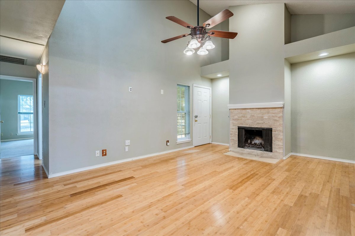 3809 Spicewood Springs Road, Unit 127 Austin, TX 78759 - Photo 5 of 29 A spacious living room features soaring vaulted ceilings and rich hardwood flooring, anchored by a charming fireplace.