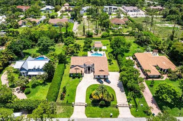 a view of a big house with a big yard and large trees