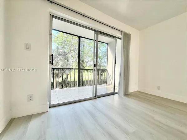 an empty room with wooden floor and a floor to ceiling window