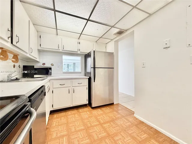 a kitchen with a refrigerator a stove top oven and cabinets