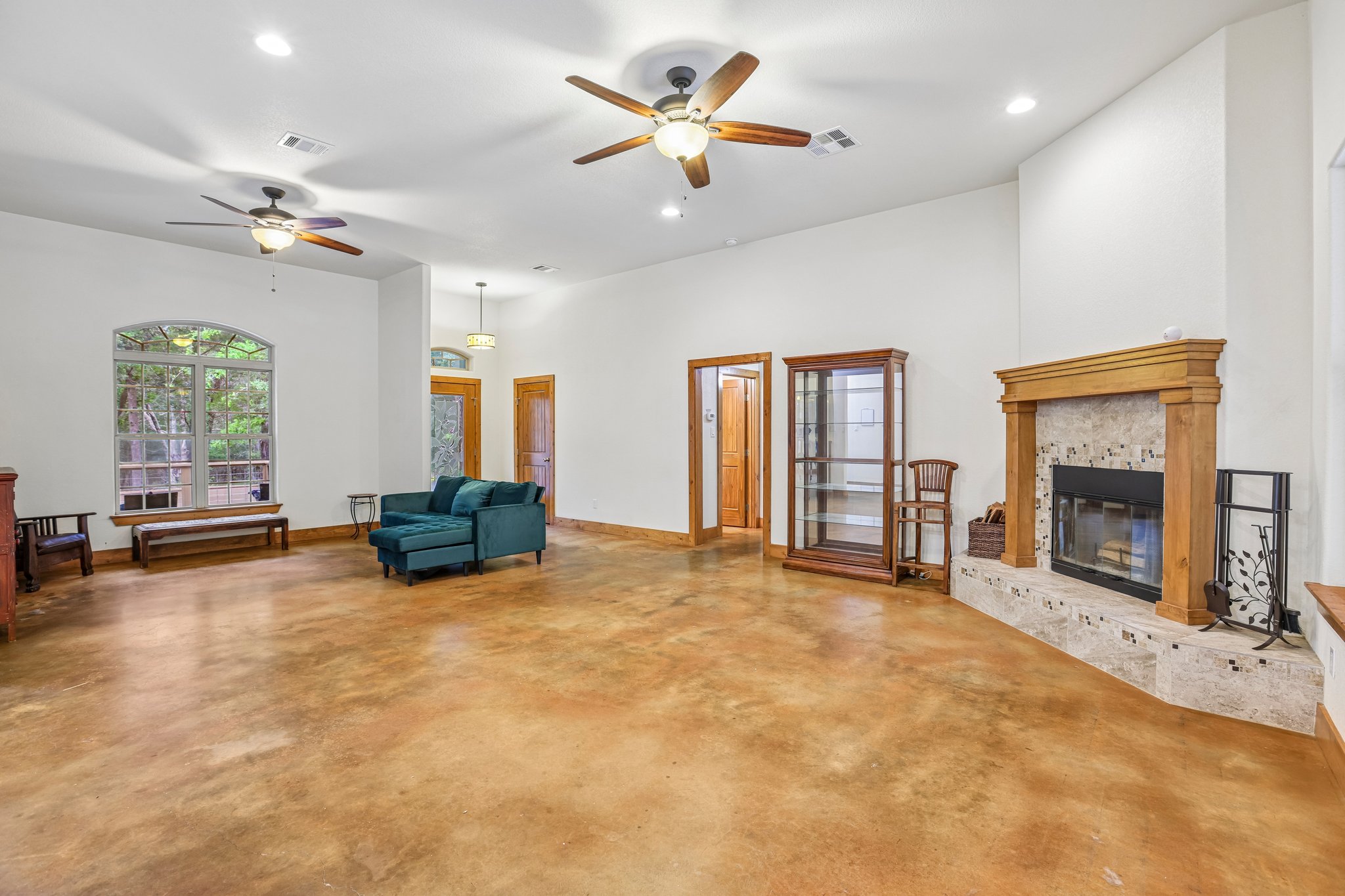 267 Corral Road Smithville, TX 78957 - Photo 10 of 40 Spacious living area featuring polished concrete flooring, a stone-surround fireplace with a wood mantle, and multiple ceiling fans