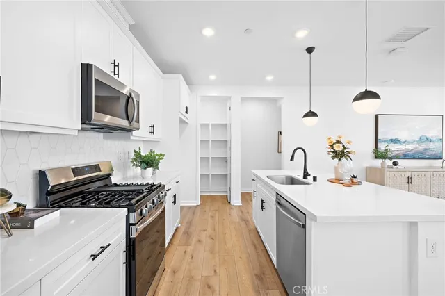 a kitchen with stainless steel appliances a sink a stove top oven a counter space and cabinets