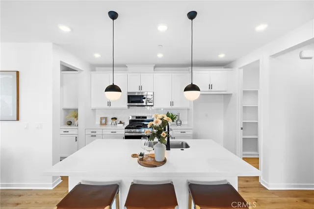 a kitchen with stainless steel appliances kitchen island granite countertop a dining table chairs and white cabinets