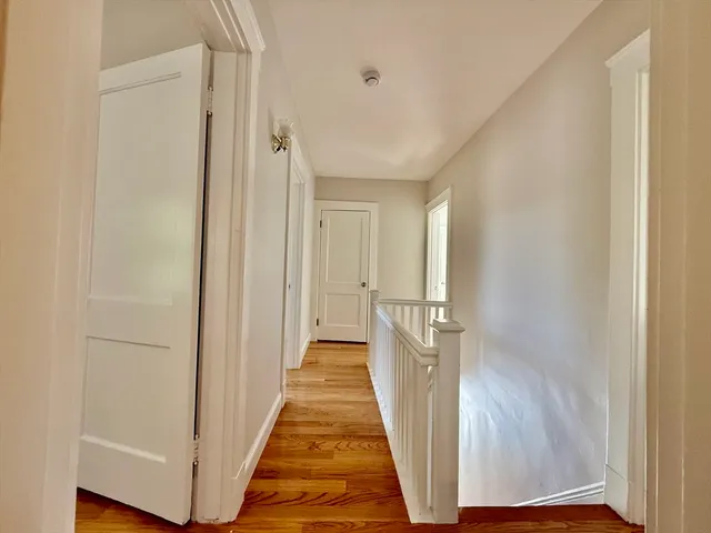 a view of a hallway with wooden floor and a bathroom