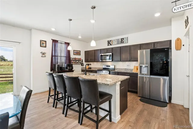 a kitchen with kitchen island a dining table chairs refrigerator and cabinets