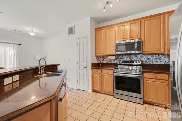 a kitchen with stainless steel appliances granite countertop a sink stove microwave and refrigerator