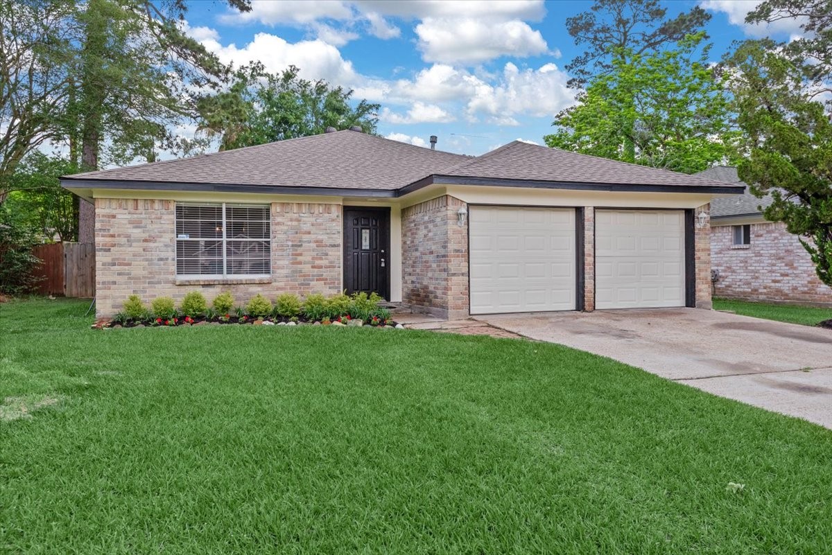 29414 Sedgefield Street Spring, TX 77386 - Photo 1 of 25 Welcome to this charming single-story brick home featuring a neatly manicured lawn, a two-car garage, and a welcoming front entrance with a small flower bed.