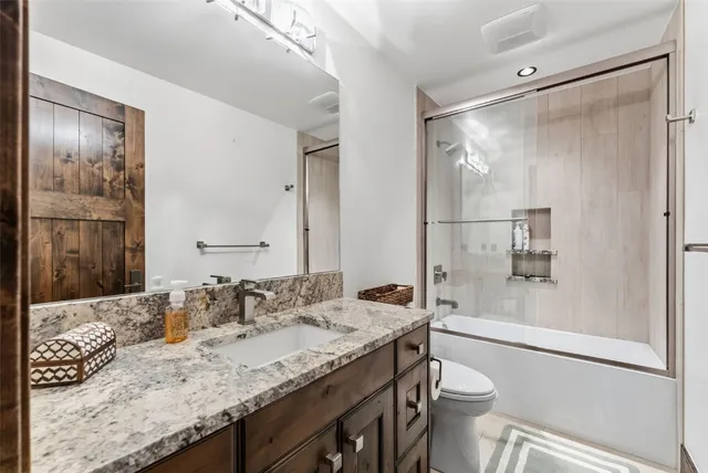 a bathroom with a granite countertop sink toilet and shower