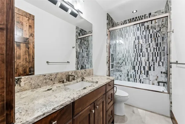 a bathroom with a granite countertop sink a toilet and shower