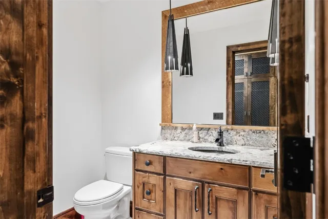 a bathroom with a granite countertop sink toilet and mirror