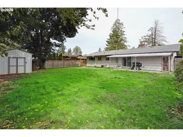 a view of a house with a big yard and large tree
