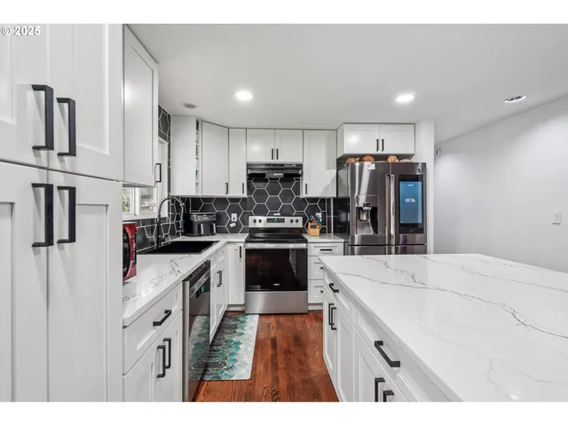 a kitchen with stainless steel appliances kitchen island granite countertop a stove top oven a sink and a refrigerator