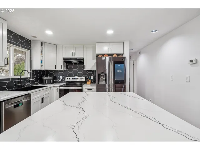 a kitchen with stainless steel appliances kitchen island a refrigerator sink and cabinets