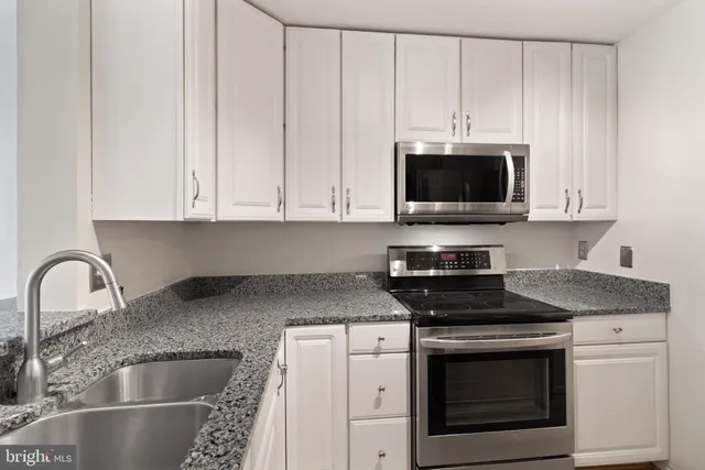 a kitchen with granite countertop white cabinets stainless steel appliances and sink