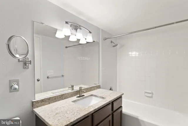 a bathroom with a granite countertop sink a mirror and a shower