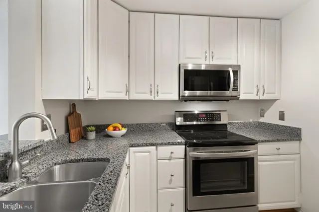 a kitchen with granite countertop a stove sink and microwave