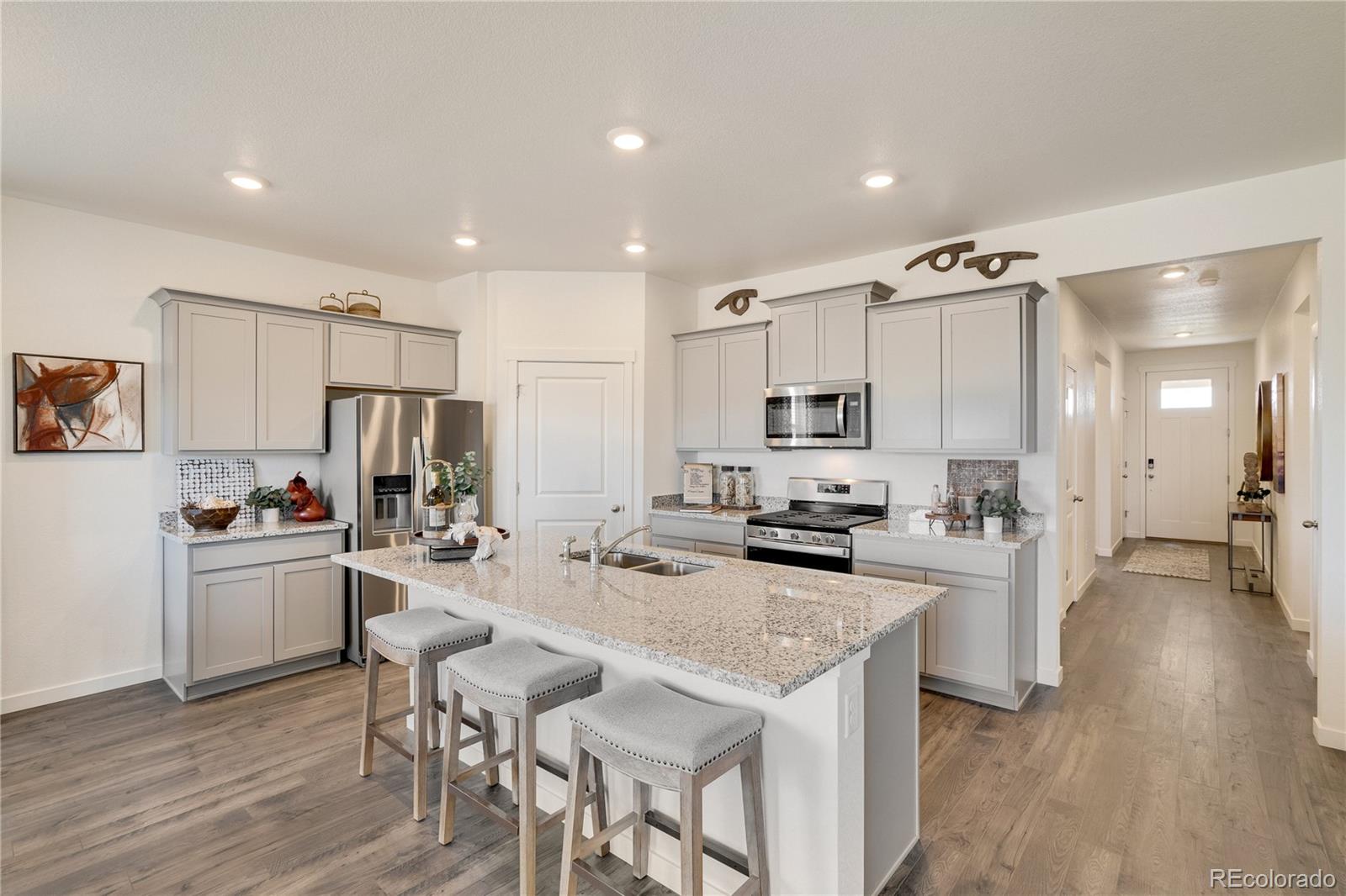 622 Sawyers Pond Drive Severance, CO 80550 - Photo 9 of 25 a kitchen with stainless steel appliances a stove a sink a refrigerator white cabinets and wooden floor