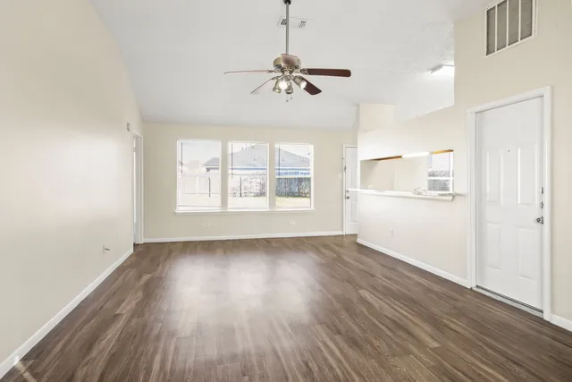 an empty room with wooden floor chandelier and windows